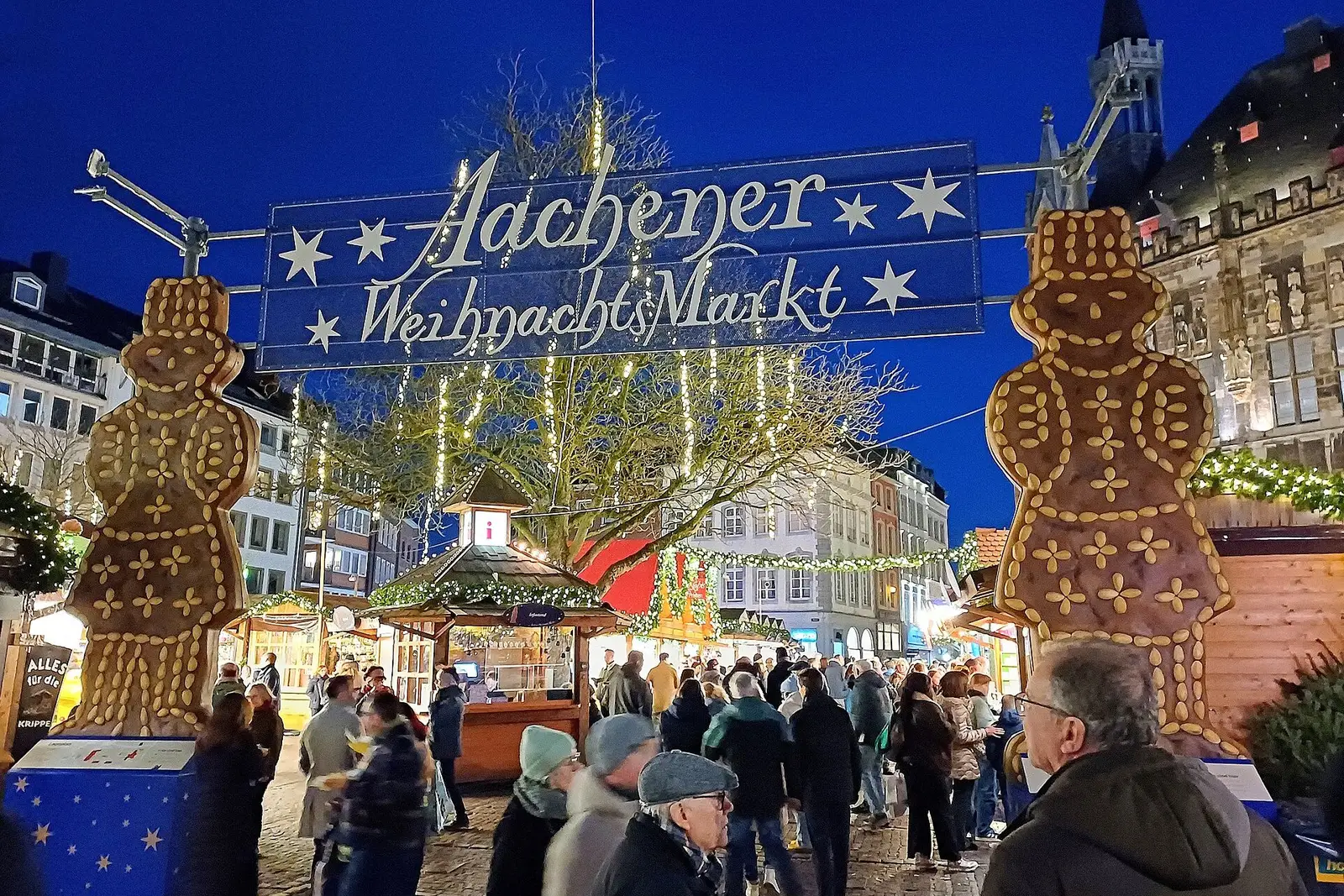 De ingang van de Aachener Weihnachtsmarkt met de verlichte poort en twee grote printenmannen