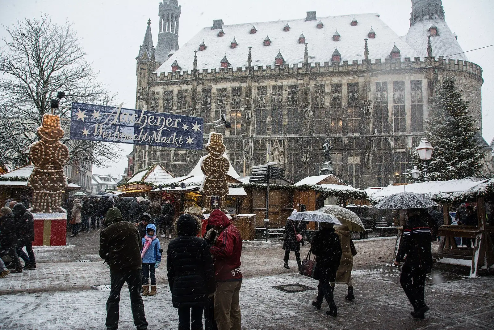 De kerstmarkt van Aken in de sneeuw, met het besneeuwde stadhuis achter de kramen