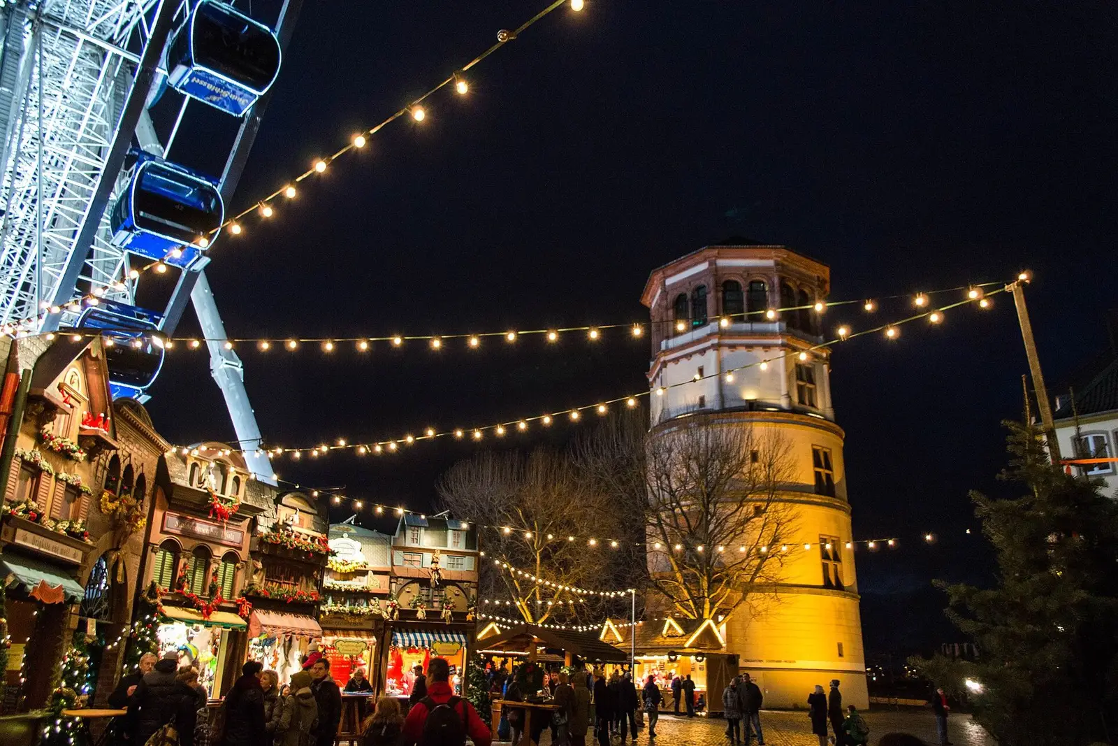 Het reuzenrad en de Schlossturm op de Burgplatz in Düsseldorf tijdens de kerstmarkt