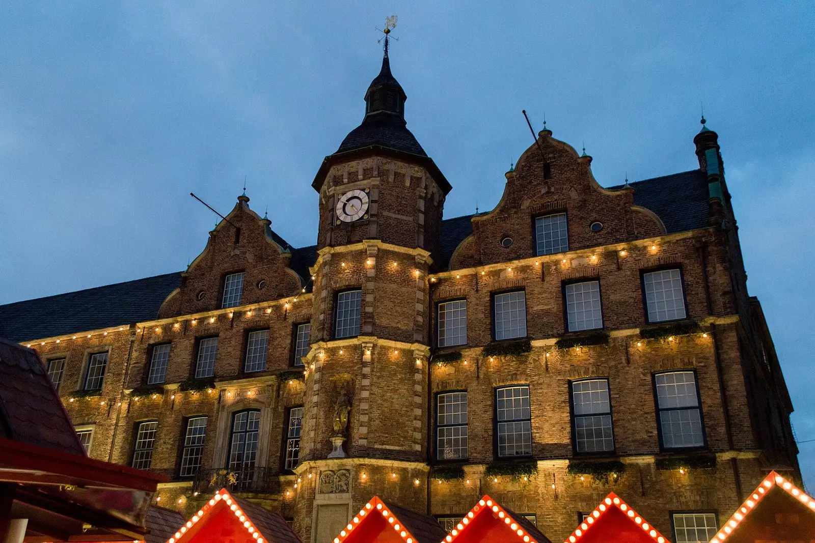 Het stadhuis van Düsseldorf bij avond, met de kerstmarkt ervoor