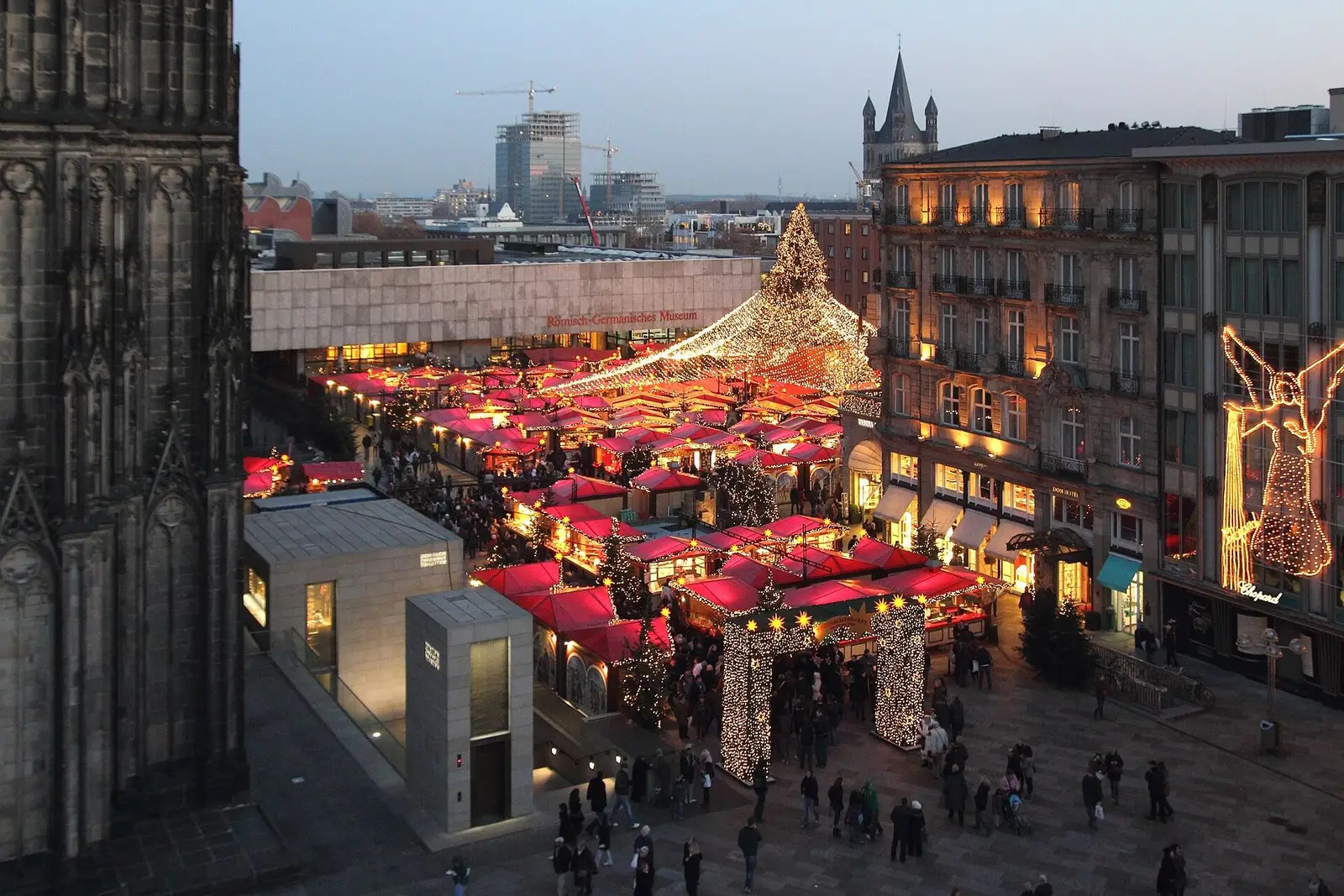 De kerstmarkt bij de Dom van Keulen van bovenaf, met de rode daken van de kramen