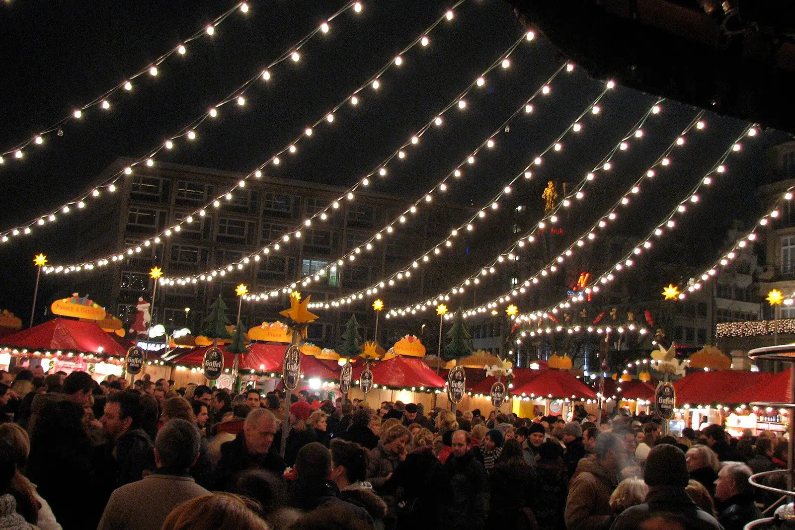 Lichtsnoeren boven een drukke kerstmarkt in Keulen bij avond