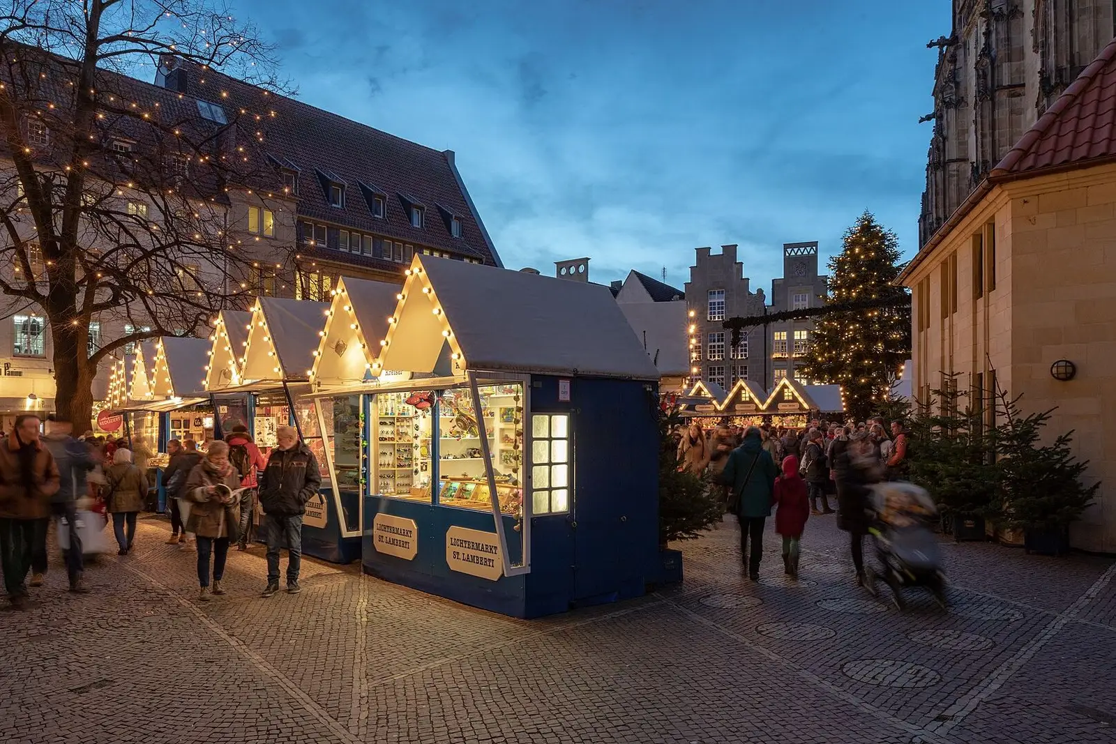 Verlichte kramen van de Lichtermarkt bij de Lambertikerk in Münster in de schemering
