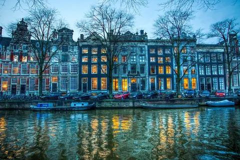 Grachtenpanden aan de Herengracht in Amsterdam, weerspiegeld in het water na zonsondergang
