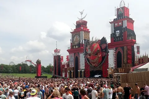 Het rode hoofdpodium van Defqon.1 bij Biddinghuizen overdag, met het publiek in de verte