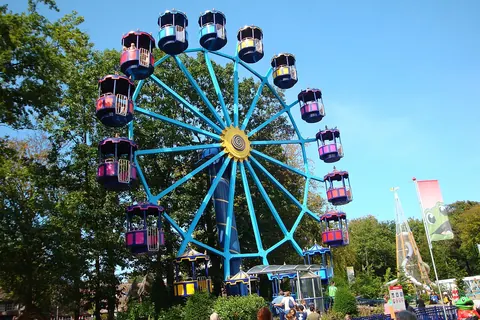 Het blauwe reuzenrad met gekleurde gondels in Duinrell, tussen de bomen