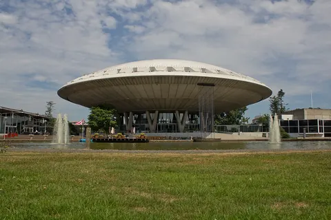 Het schotelvormige Evoluon in Eindhoven met een grasveld en fonteinen ervoor