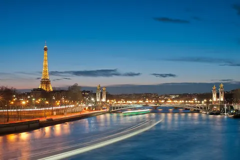 De Eiffeltoren en de Pont Alexandre III over de Seine in Parijs bij avond