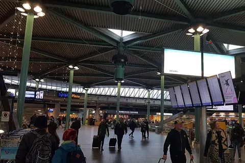 De hal van Schiphol Plaza met reizigers en de vertrekborden