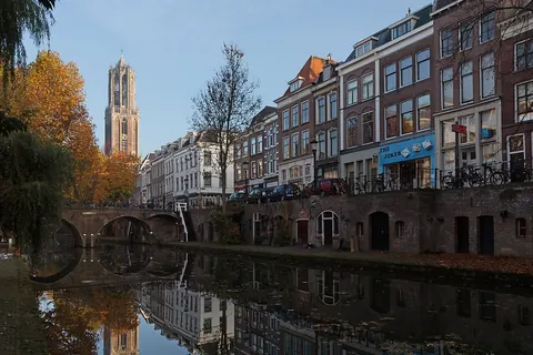 De Domtoren boven de Oudegracht in Utrecht, met herfstbomen en een brug